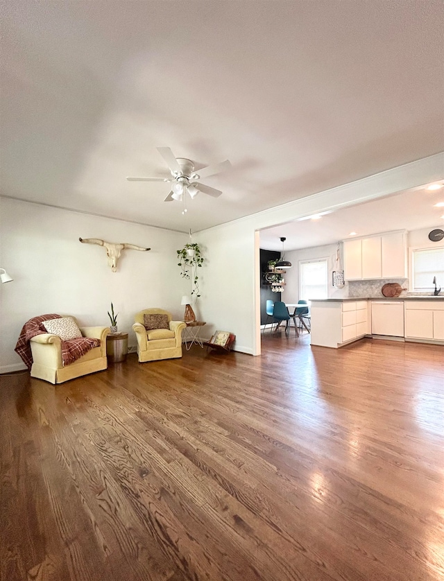 unfurnished living room featuring dark wood-type flooring, ceiling fan, and sink