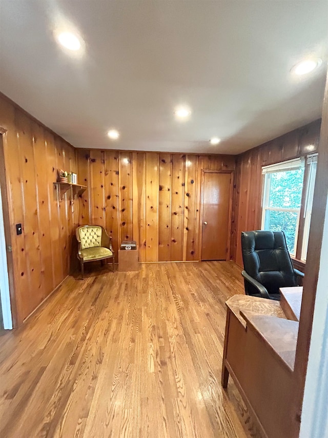 sitting room featuring light wood-type flooring and wooden walls