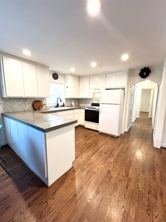 kitchen featuring white appliances, dark hardwood / wood-style flooring, kitchen peninsula, sink, and white cabinets