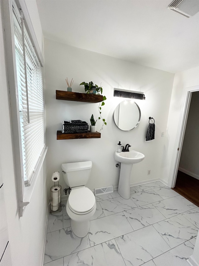 bathroom featuring toilet, a wealth of natural light, and sink