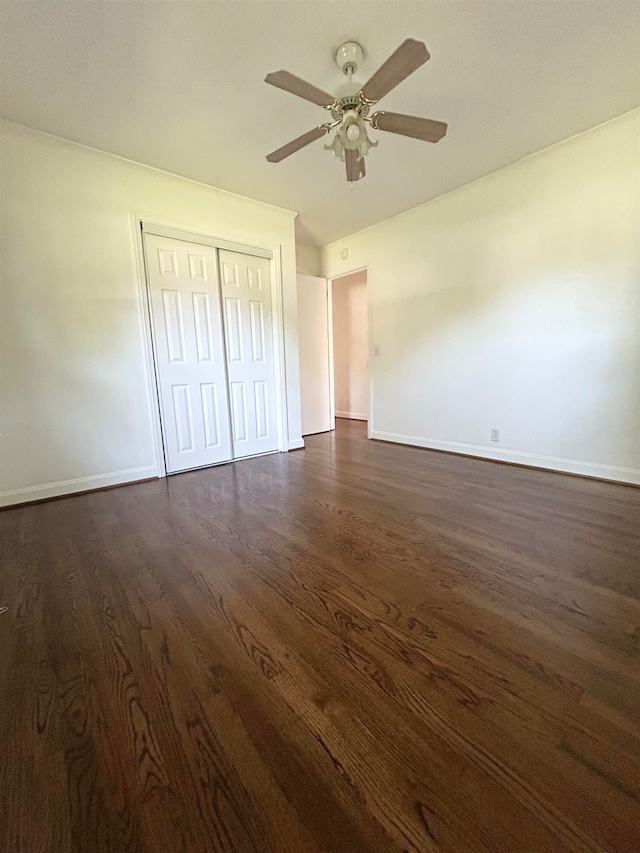 unfurnished bedroom featuring dark wood-type flooring, a closet, and ceiling fan