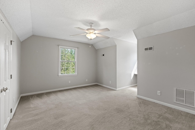 carpeted empty room featuring vaulted ceiling, a textured ceiling, and ceiling fan