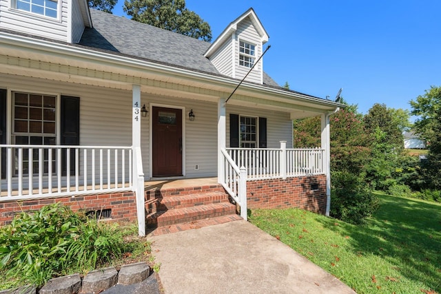 doorway to property with a porch and a yard