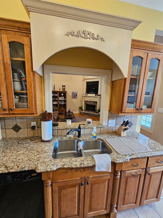 kitchen with dishwasher, backsplash, sink, and light stone countertops