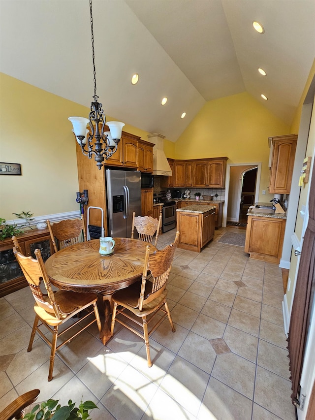 dining space featuring high vaulted ceiling, light tile patterned floors, and an inviting chandelier