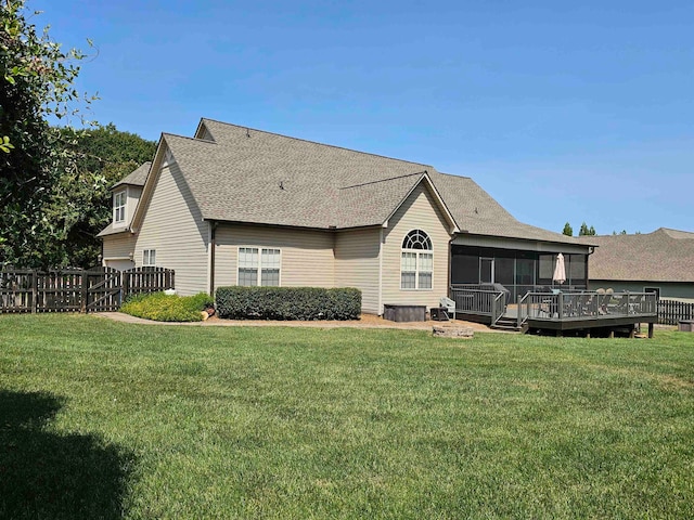 back of property featuring a lawn, a wooden deck, and a sunroom