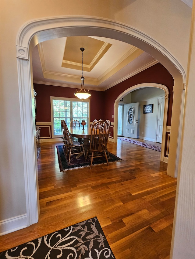 unfurnished dining area with hardwood / wood-style floors, a tray ceiling, and ornamental molding