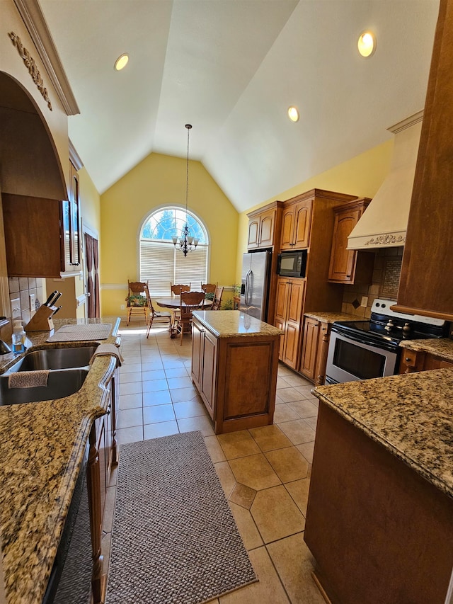 kitchen featuring stainless steel appliances, light tile patterned floors, a kitchen island, hanging light fixtures, and vaulted ceiling