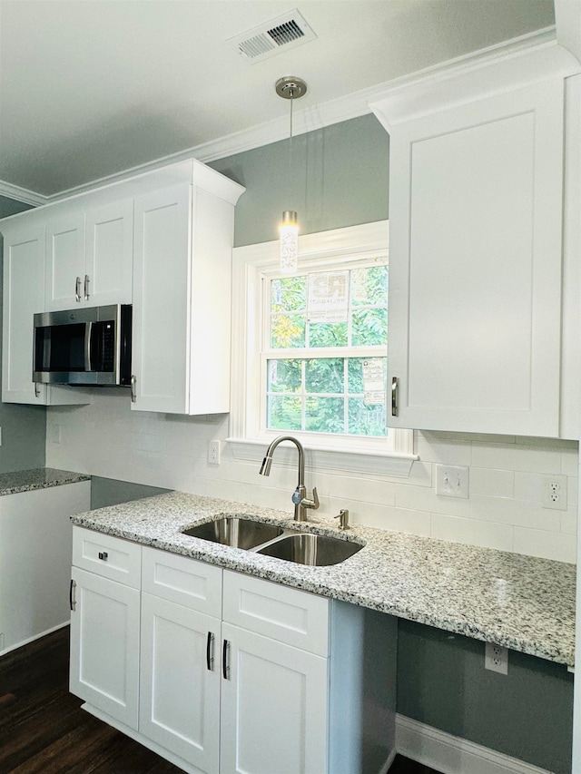 kitchen with crown molding, hanging light fixtures, sink, dark wood-type flooring, and white cabinets