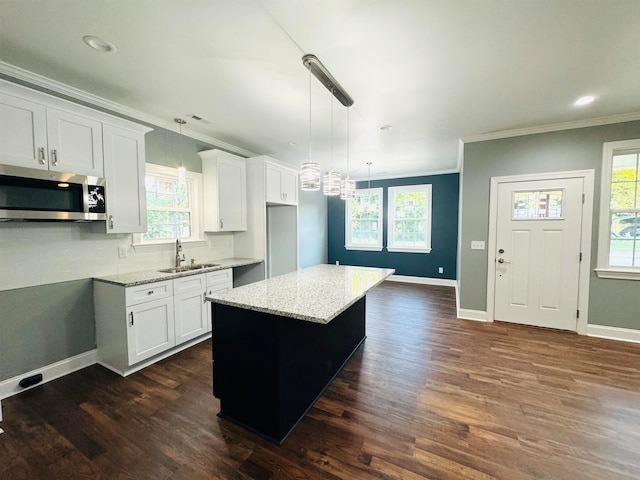 kitchen with a kitchen island, light stone counters, decorative light fixtures, and white cabinets