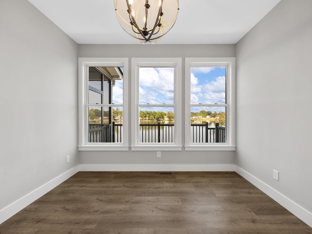 unfurnished dining area featuring a chandelier and dark hardwood / wood-style flooring