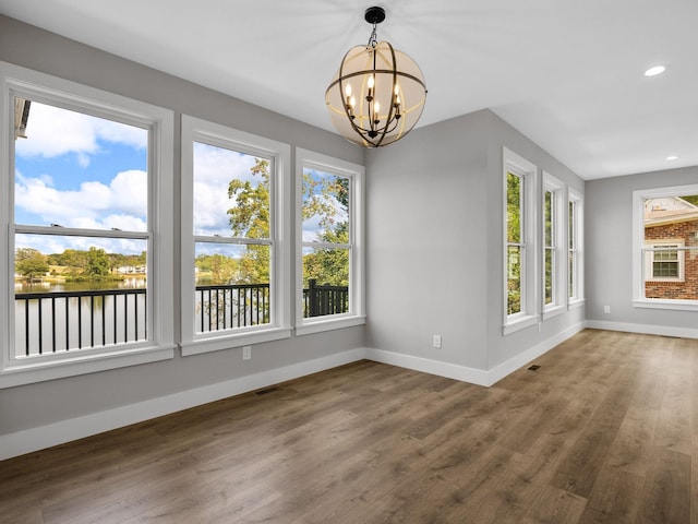 unfurnished dining area with hardwood / wood-style floors and a notable chandelier