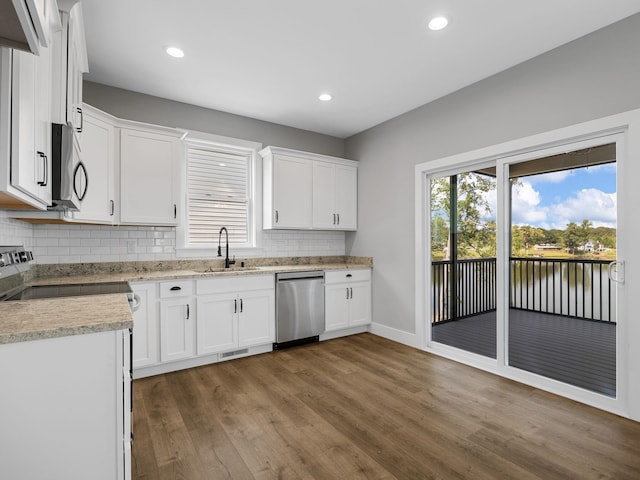 kitchen with dark hardwood / wood-style flooring, backsplash, appliances with stainless steel finishes, sink, and white cabinetry