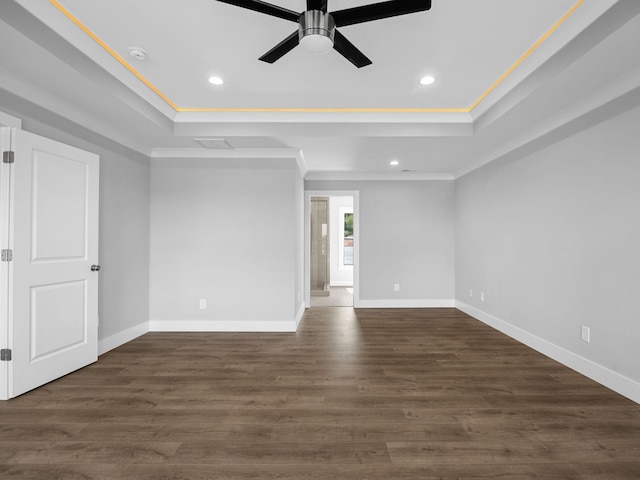 spare room with ornamental molding, dark hardwood / wood-style flooring, a tray ceiling, and ceiling fan