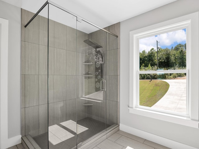 bathroom with a wealth of natural light and a shower with shower door