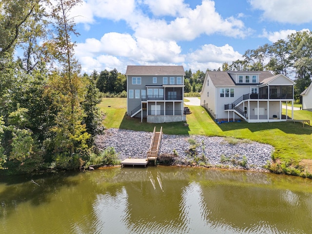 rear view of property with a water view, a yard, and a sunroom