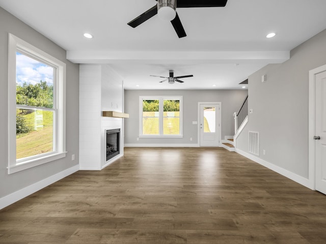 unfurnished living room featuring ceiling fan, a large fireplace, and dark hardwood / wood-style floors