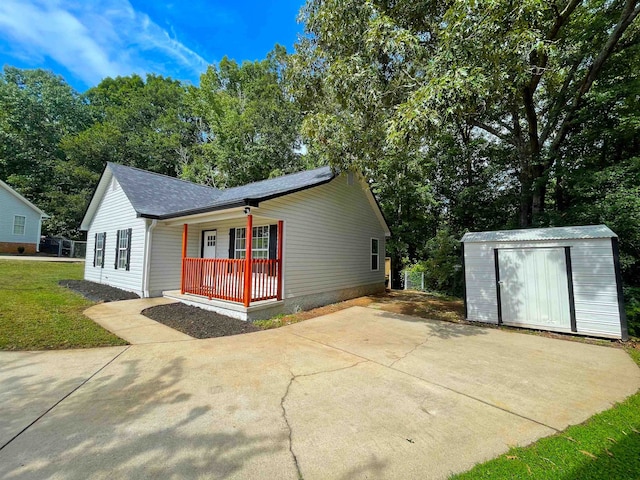 view of front of home featuring covered porch, a storage unit, and a front lawn