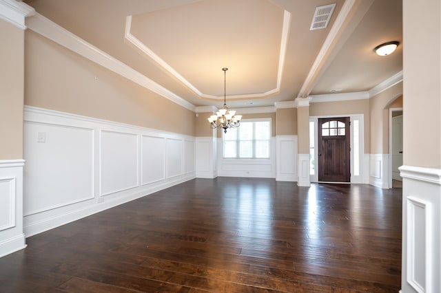 interior space featuring dark wood-type flooring, a tray ceiling, crown molding, and a notable chandelier