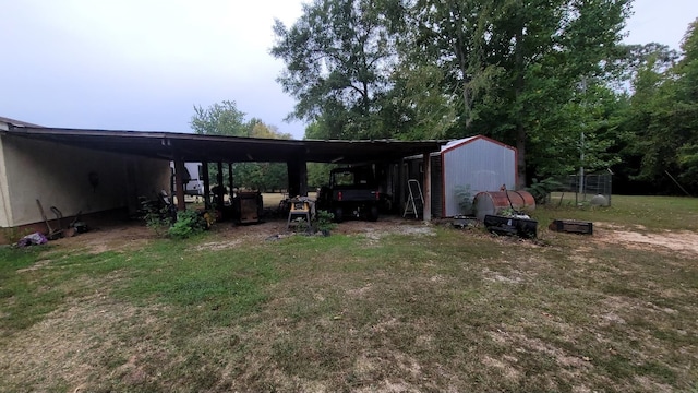 view of yard featuring a carport, driveway, and an outdoor structure