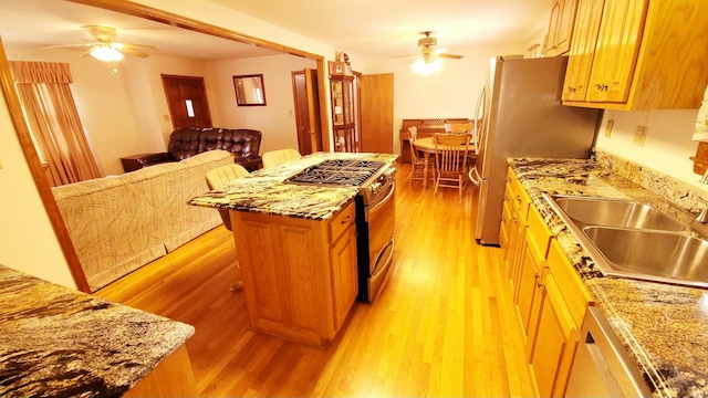 kitchen featuring light wood finished floors, stainless steel appliances, a ceiling fan, and a sink