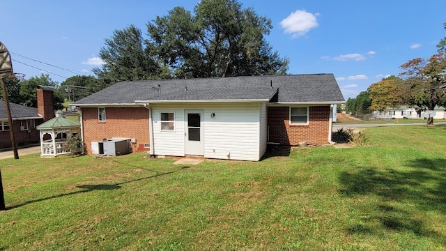 rear view of property with brick siding, central AC unit, and a lawn