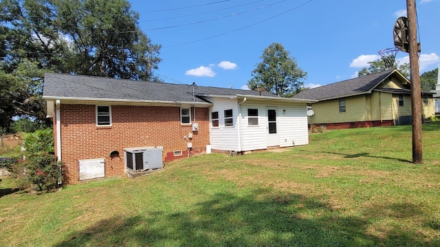exterior space with a yard, central AC unit, brick siding, and a chimney