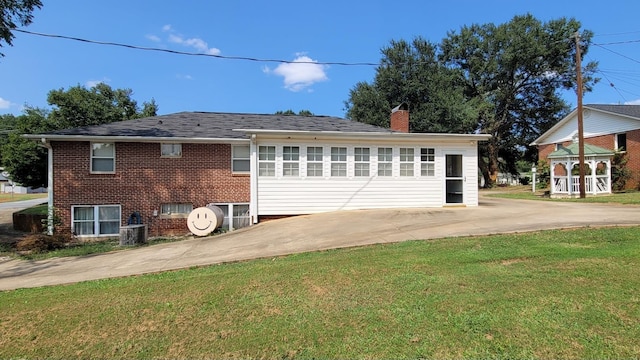 view of home's exterior with brick siding, an attached garage, a lawn, driveway, and heating fuel