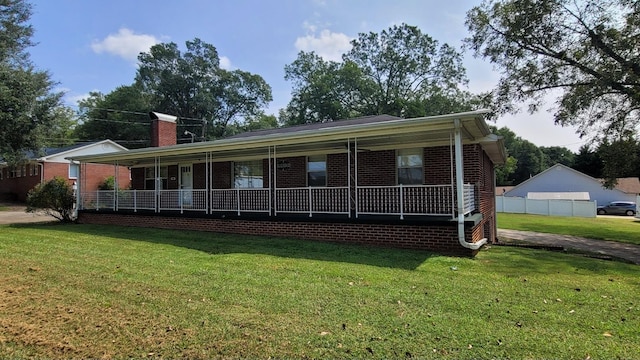view of front of property with a detached carport, a front lawn, covered porch, and a chimney