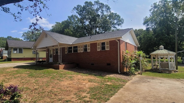 view of front facade with a gazebo, a front lawn, brick siding, and crawl space