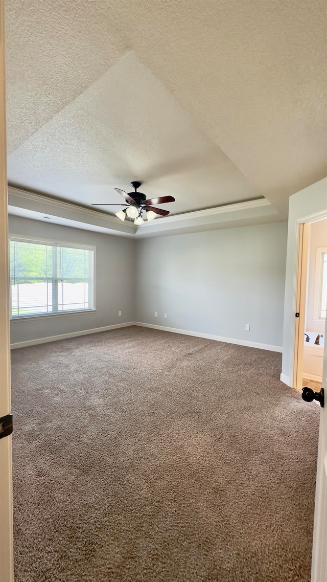 carpeted empty room with a raised ceiling, a textured ceiling, and ceiling fan