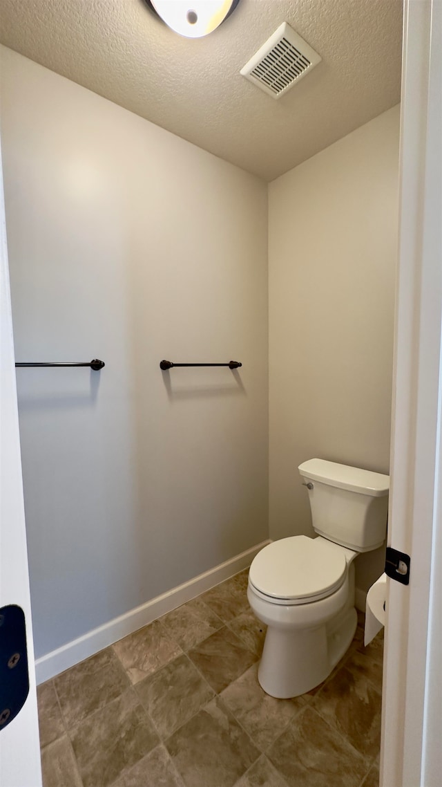 bathroom with toilet and a textured ceiling