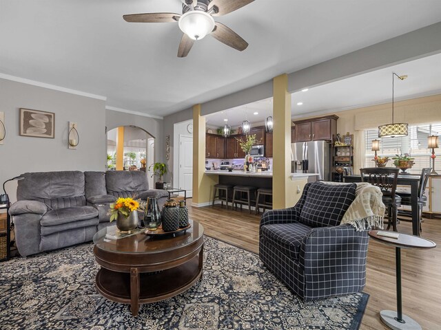 living room with light wood-type flooring, ceiling fan, and crown molding