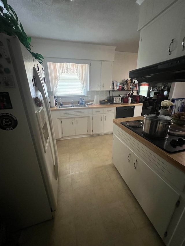 kitchen with white cabinetry, white fridge with ice dispenser, black stovetop, and a textured ceiling