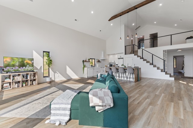 living room featuring light hardwood / wood-style flooring, beamed ceiling, and high vaulted ceiling