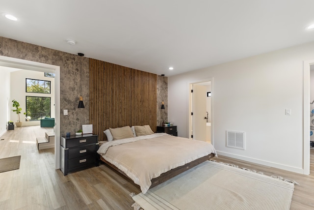 bedroom with ensuite bathroom and light hardwood / wood-style floors