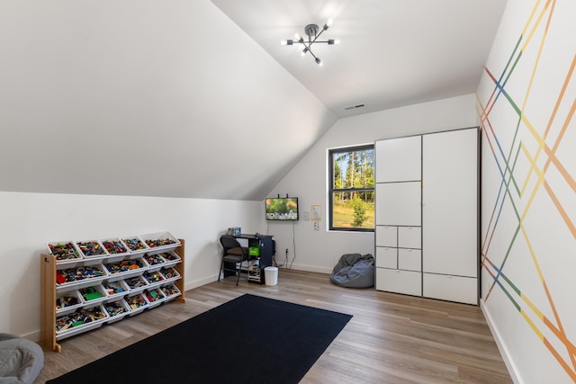 exercise area with lofted ceiling, a notable chandelier, and hardwood / wood-style floors