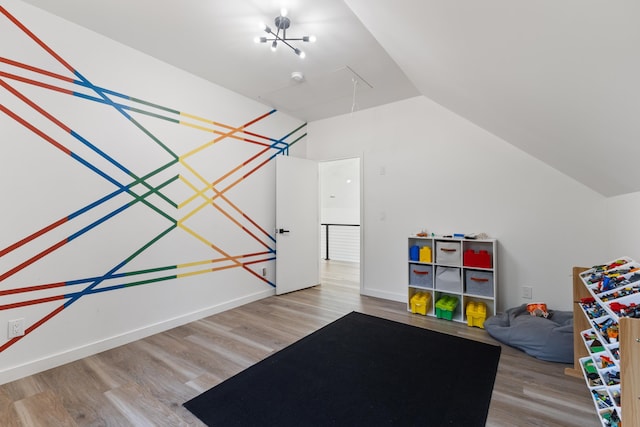 playroom featuring lofted ceiling, wood-type flooring, and a notable chandelier