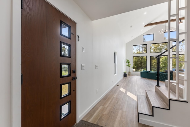 entrance foyer featuring a towering ceiling, beamed ceiling, and light wood-type flooring