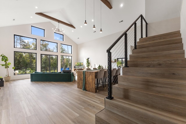 stairway with high vaulted ceiling, hardwood / wood-style flooring, an inviting chandelier, and beam ceiling