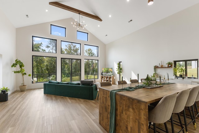 interior space featuring beamed ceiling, high vaulted ceiling, a chandelier, light hardwood / wood-style flooring, and a breakfast bar