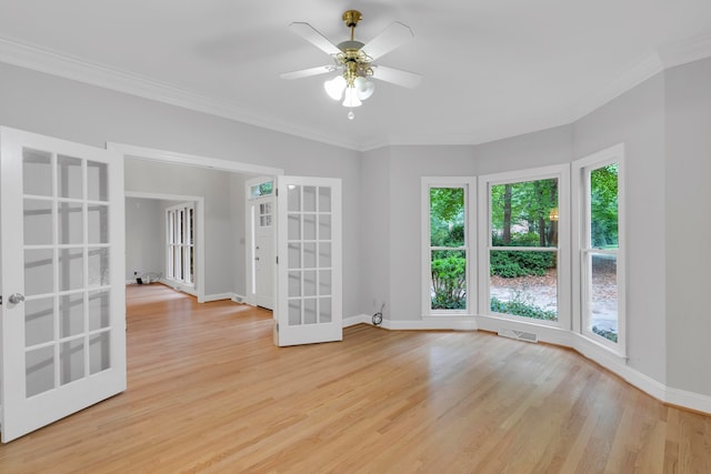 empty room with french doors, light hardwood / wood-style floors, ceiling fan, and crown molding