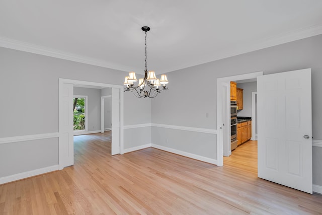 spare room featuring crown molding, light hardwood / wood-style flooring, and a chandelier