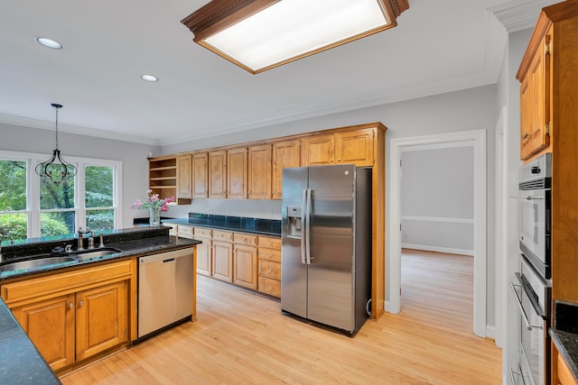 kitchen featuring stainless steel appliances, crown molding, sink, pendant lighting, and light hardwood / wood-style flooring