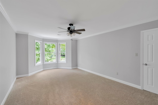 spare room with ceiling fan, crown molding, and light carpet