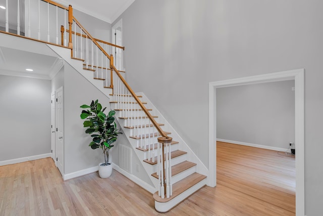 staircase with hardwood / wood-style floors and ornamental molding