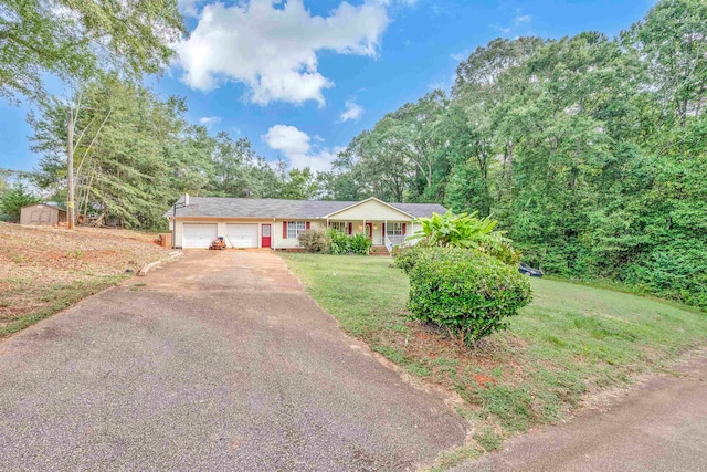 single story home with a front yard, a garage, a porch, and a shed