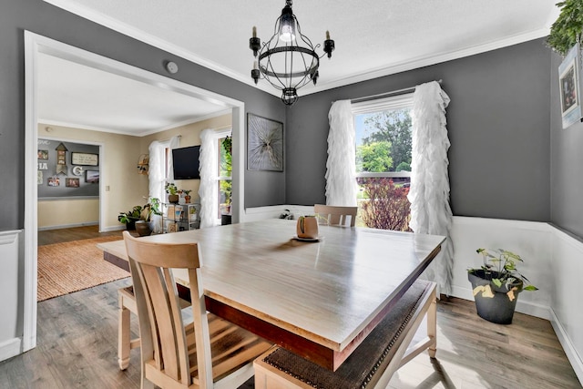 dining space with ornamental molding, hardwood / wood-style floors, and a chandelier