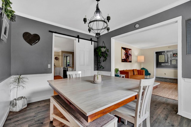 dining area with a barn door, ornamental molding, and dark hardwood / wood-style floors