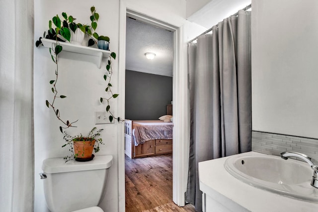 bathroom with wood-type flooring, vanity, toilet, and a textured ceiling